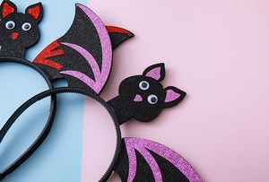 Close-up of Halloween bat wing headband with glitter foam details on colorful background