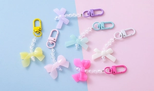 Close-up of colorful acrylic bow and pearl charms on pastel background