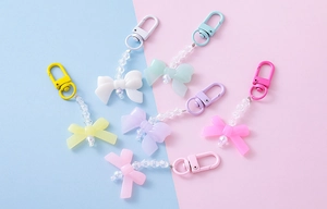 Detailed view of colorful acrylic bow pendants with pearl beads and matte carabiners