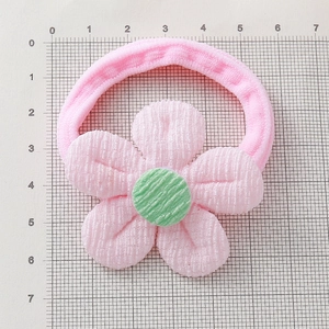Élastique à cheveux fleur rose avec pétales en tissu sur une planche de mesure graduée