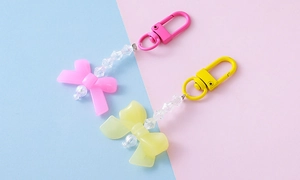 Close-up of pink and yellow acrylic bow keychains with colorful pearls and lobster clasps