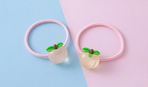 Detailed macro of two cute pink elastic hair ties with 3D resin fruit peach charms