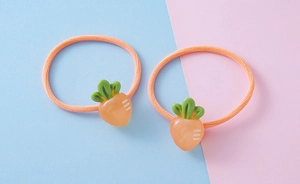 Close-up of orange carrot resin charms on elastic hair ties for girls on dual-tone background