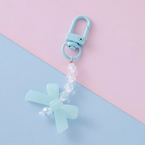 Close-up of candy-colored acrylic bow pendant with pearls on a pastel dual-tone background