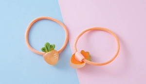 Close-up of two elastic orange hair ties featuring cute resin carrot fruit charms