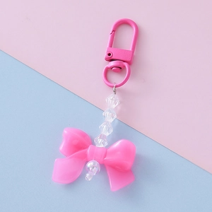 Close-up of pink acrylic bow keychain with transparent beads and metal lobster clasp