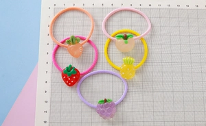 Detail of five elastic hair bands with 3D resin fruit charms including strawberry and grape