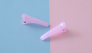 Détail montrant une paire de pinces à cheveux roses translucides sur fond bleu pastel