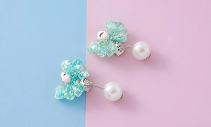 Detail of sweet green resin bow clip-on earrings with shimmering glitter and pearl drops