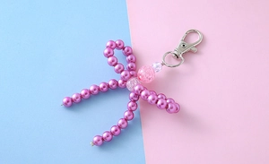 Detalle de colgante de lazo de perlas púrpuras hecho a mano con cuenta rosa y cierre de plata