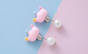 Detail showing pink cartoon crown clip-on earrings with decorative faux pearl drop