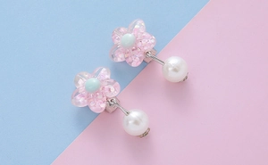 Detailed view of pink resin flower clip-on earrings with glitter and small pearl accents