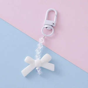 Close-up of white resin bow keychain with iridescent beads and transparent faceted crystals