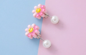 Detail of pink resin flower ear clips with white faux pearls and smiling face for kids