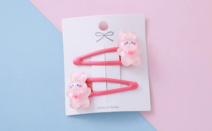Close-up of pink resin bunny hair clips with cute bows on a blue and pink background
