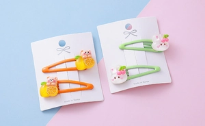 Close-up of cute fruit and rabbit resin charms on colorful metal hair clips for girls