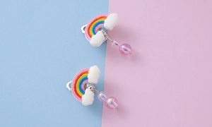 Detail of colorful rainbow resin ear clips with white clouds and pink iridescent beads