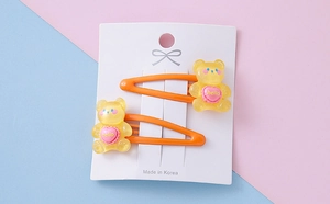 Close-up of yellow resin gummy bear hair clips with hello heart on a display card