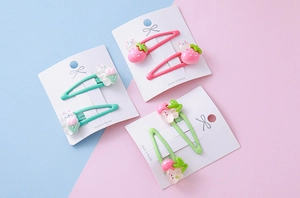 Close-up of cute strawberry and rabbit hair clips for girls on colorful card