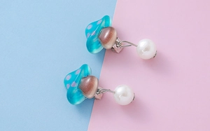 Detailed view of blue spotted mushroom ear clips with hanging white round pearls