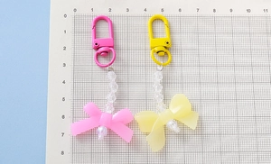 Detail view of pink and yellow acrylic bow keychains with scale ruler for size measurement