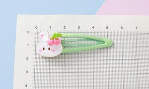 Close-up of cute strawberry rabbit hair clip measuring 5.5cm on a grid scale board