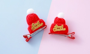 Detalle de mini gorros de Navidad de punto rojos con texto dorado y pinzas de metal para pelo