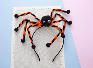 Detail of Halloween spider headband with fuzzy orange and black legs on grid background