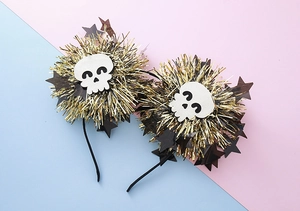 Detail view of Halloween headband with gold metallic pom-poms and cute skull icons