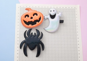Lot de 3 barrettes Halloween avec citrouille, fantôme et araignée sur un fond quadrillé