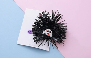 Detail of Halloween hair clip with black tinsel pom and white spider on purple metal clip