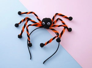 Close-up of a Halloween spider headband with orange legs and googly eyes for kids