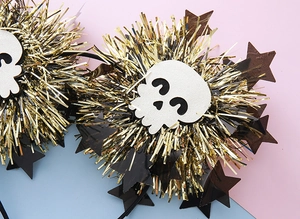 Close-up of Halloween headband featuring white skulls and gold tinsel stars on a colorful base