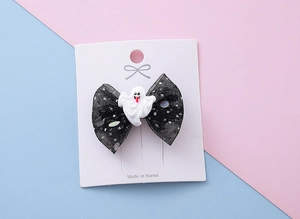 Détail de la barrette à nœud en maille pailletée avec un charme de fantôme blanc