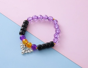 Makroaufnahme eines Halloween-Perlenarmbands mit silbernem Fledermaus-Anhänger und Perlen