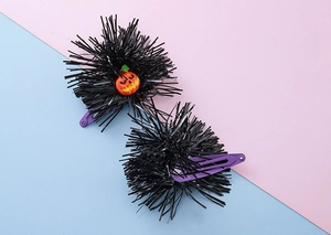 Detail of Halloween hair clips with black tinsel pom and orange pumpkin smiley face decor