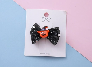 Détail de pince à cheveux Halloween avec nœud en résille noire et breloque citrouille sur carte