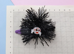 Detail view of a Halloween spider hair clip with purple clip and black tinsel fringe decor