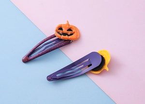 Détail d'une pince à cheveux citrouille d'Halloween avec paillettes mauves et émail orange