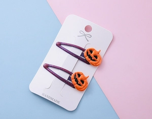 Détail de pinces à cheveux Halloween violettes à paillettes avec motifs citrouilles orange