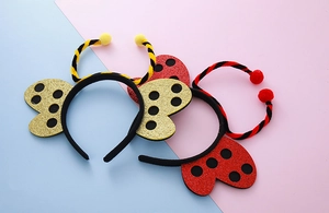 Dettaglio di cerchietti glitter ape e coccinella con pompon per costumi da festa