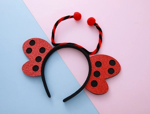 Dettaglio delle ali di coccinella con paillettes rosse e antenne sul cerchietto