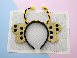 Dettaglio del cerchietto ape con antenne a strisce e ali di coccinella con paillettes