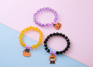 Close-up of three colorful Halloween beaded bracelets with pumpkin and black cat charms