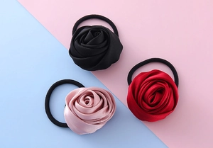 Vista dettagliata degli elastici per capelli con rose in raso nero, bordeaux e rosa chiaro