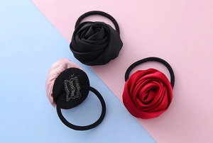 Dettaglio di tre elastici per capelli con rose in raso fatte a mano in nero e bordeaux