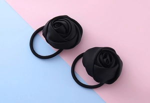 Dettaglio di due eleganti elastici per capelli con rose in raso nero ad alta elasticità