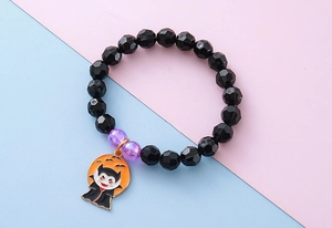 Macro detail of Halloween beaded bracelet featuring a cute vampire enamel pumpkin charm