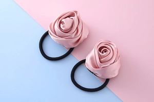 Dettaglio di due elastici per capelli a forma di rosa in raso rosa con bande nere