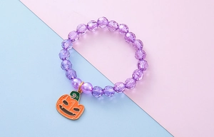 Close-up of Halloween pumpkin charm with purple faceted acrylic beads on kids bracelet